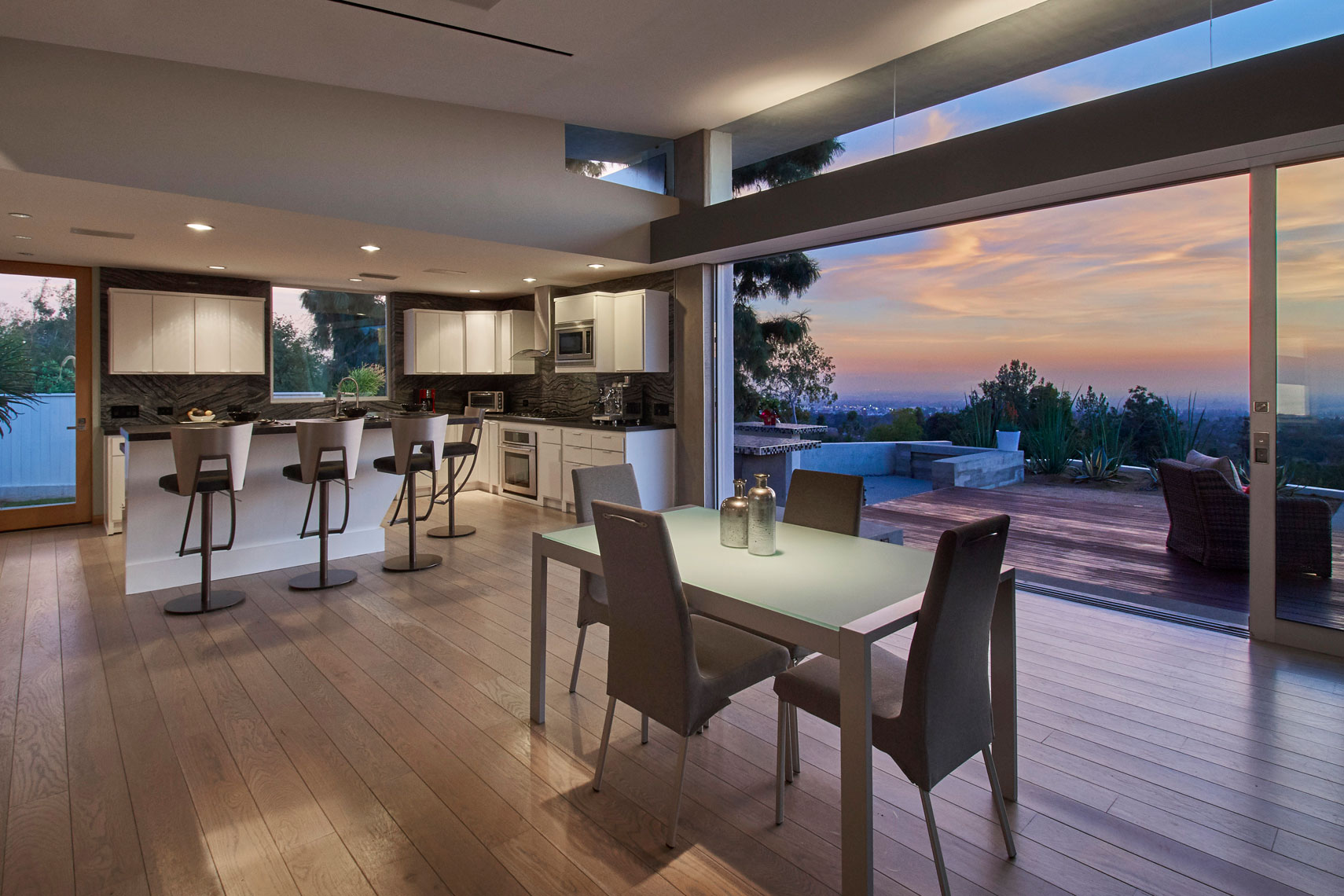 Architectural-photography-of-dining-room-and-kitchen-of-contemporary-Los-Angeles-home-with-open-sliding-glass-door-to-deckatsunset-Joe-Atlas-architectural-photographer-Los-Angeles.