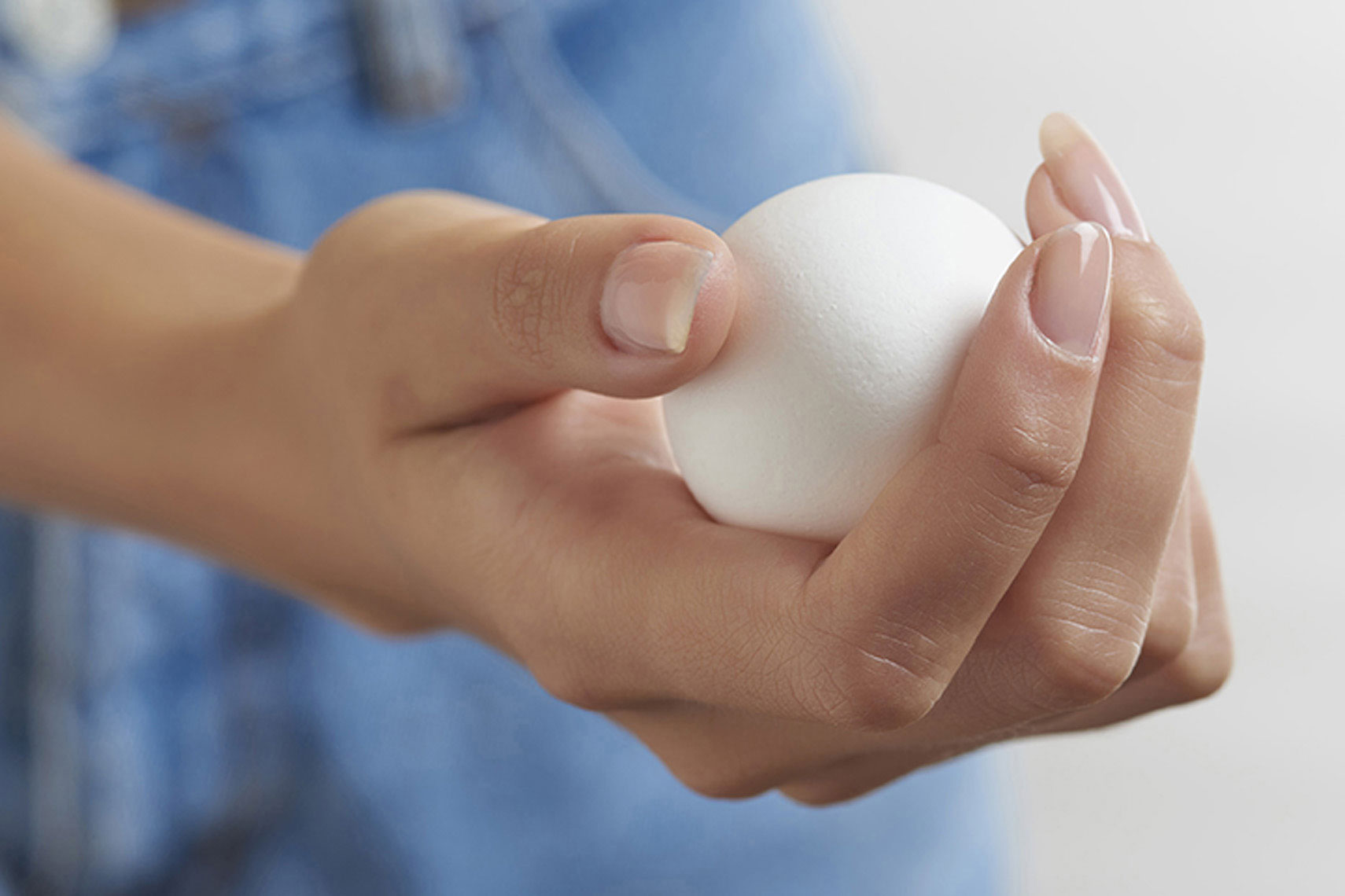 Female-hand-holding-fresh-white-egg-by-Joe-Atlas-food-photography.