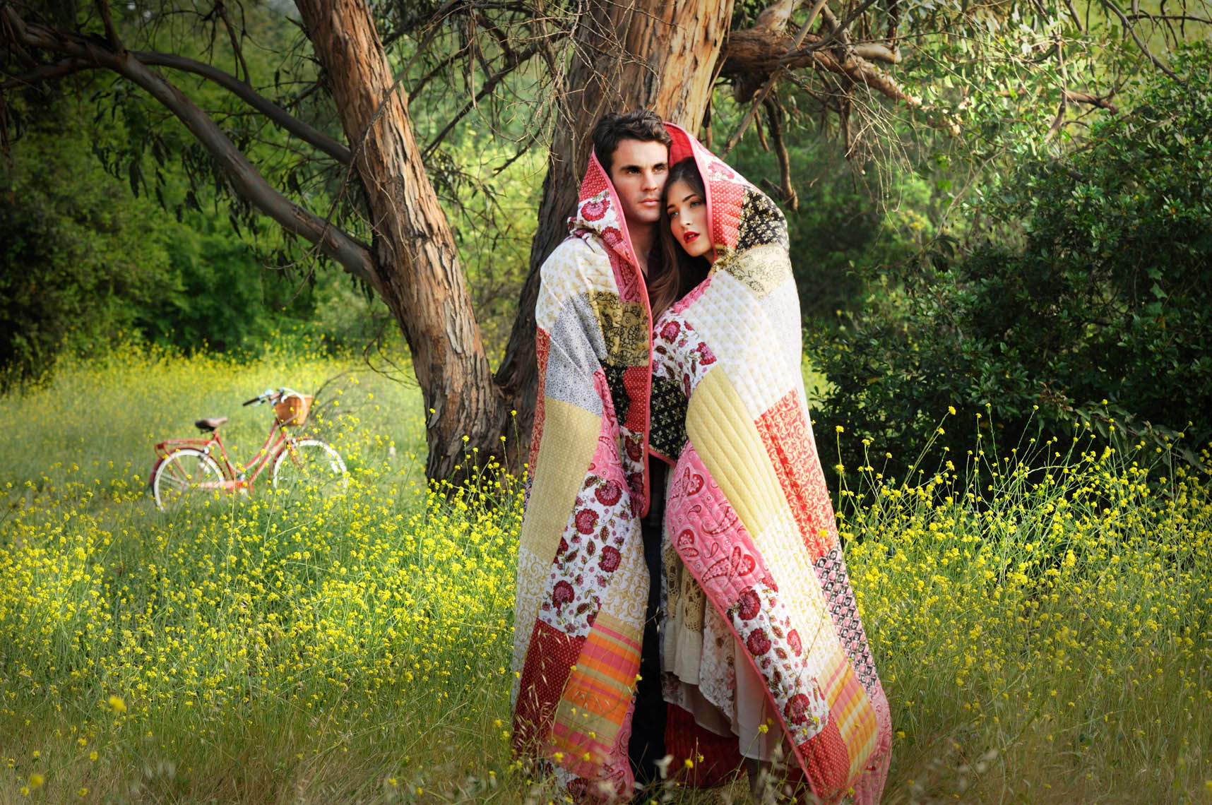 Portrait-of-young-couple-with-blanket-wrapped-around-them-in-a-field-of-yellow-flowers-lifestyle-photographer.