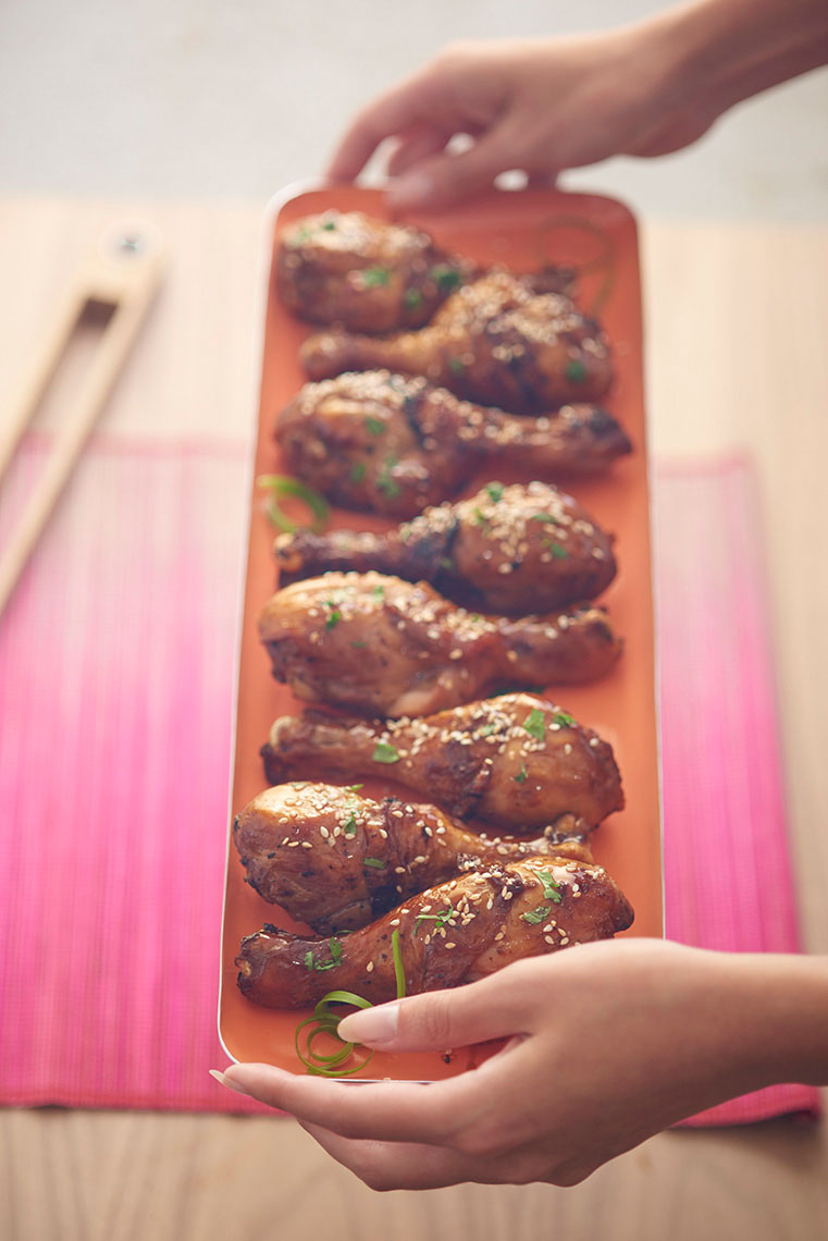 Womans-hands-holding-a-tray-of-tereyaki-drumsticks-with-sesame-seeds-by-Los-Angeles-food-photographer