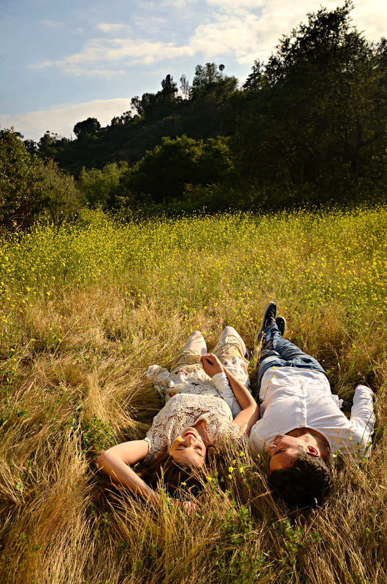 Young-couple-enjoying-a-spring-afternoon-laying-in-grassy-field-with-yellow-wildflowers-by-lifestyle-photographer-Joe-Atlas.