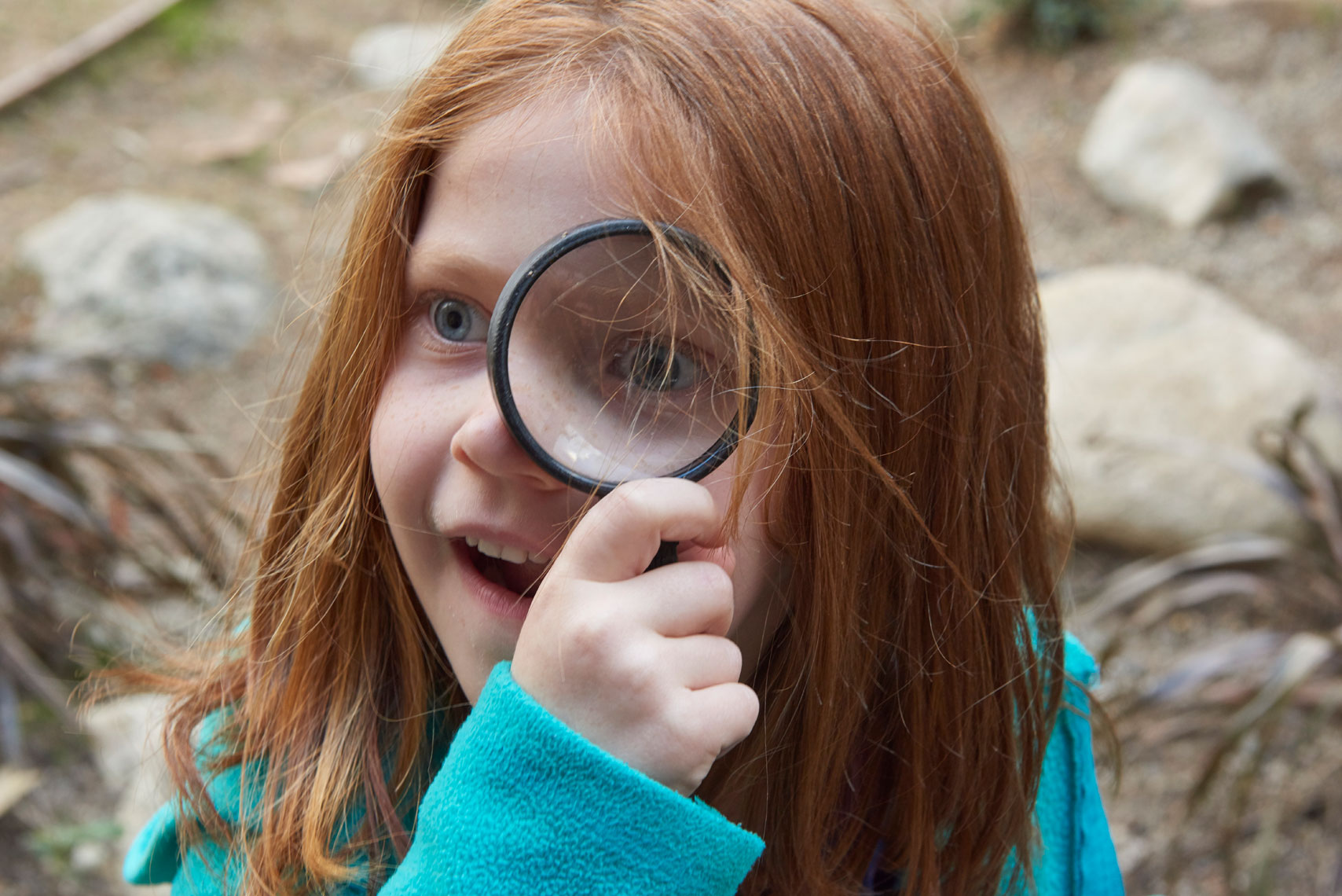 Young_girl_looking_through_magnifying_glass-by-annual-report-photographer-Joe-Atlas.